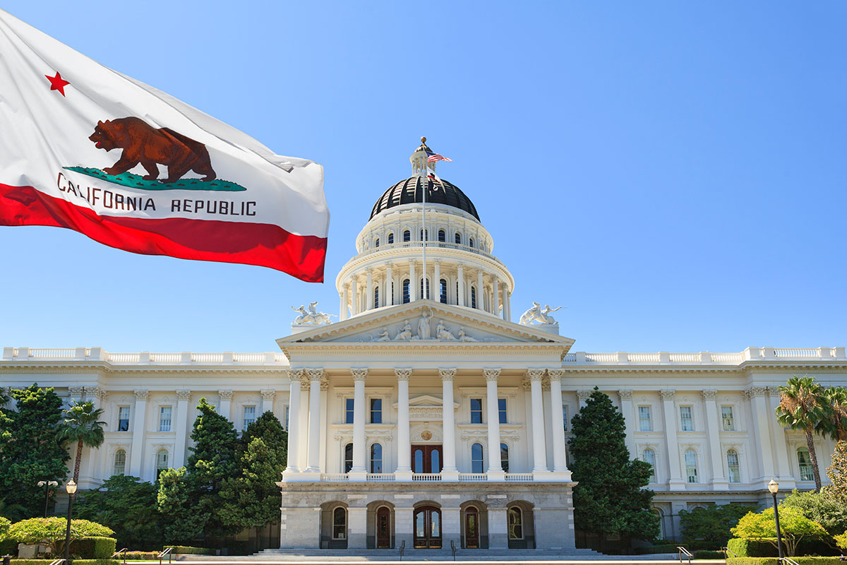 The California state flag waving in front of the State capitol building